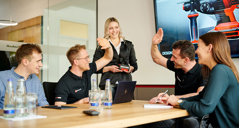 A group of people sitting in a meeting and giving each other a high five. 
