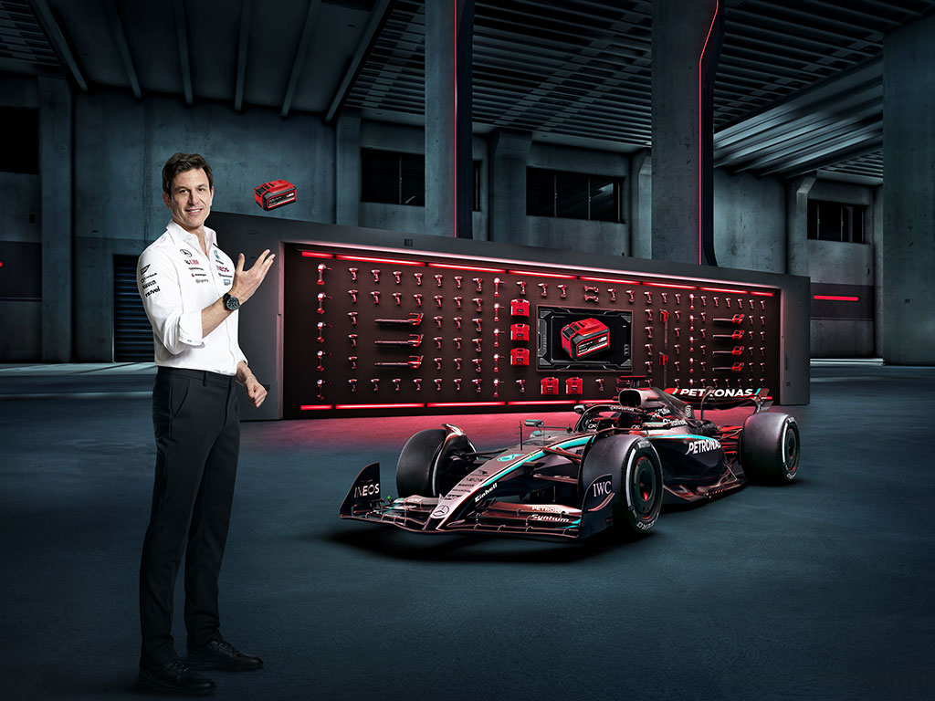 Toto Wolff throws a battery into the air next to a Formula One car.