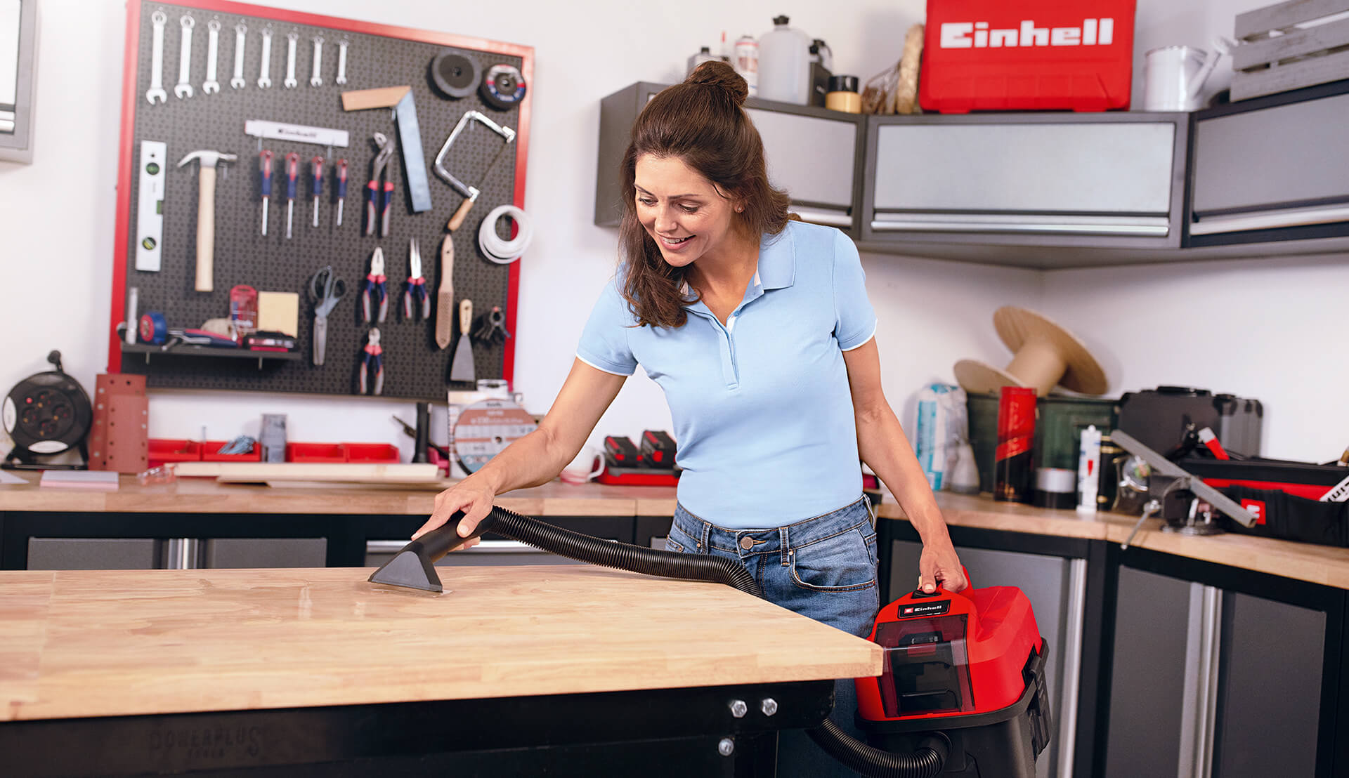 woman cleaning the workshop with a cordless wet / dry vacuum cleaner