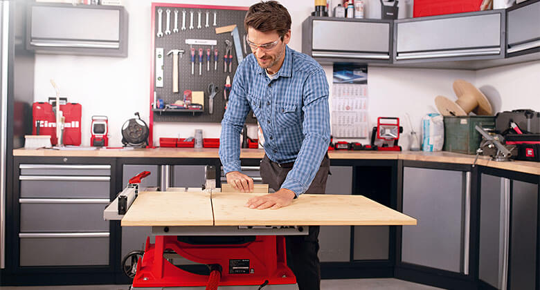 man cuts a wooden board in a workshop