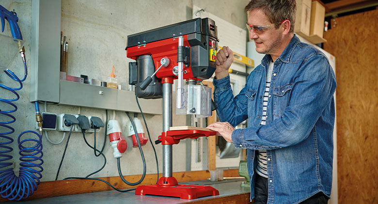 A man working with a pillar drill.